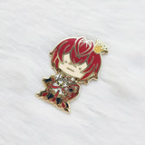 Metallic character pin with red hair and a crown on a white fabric background